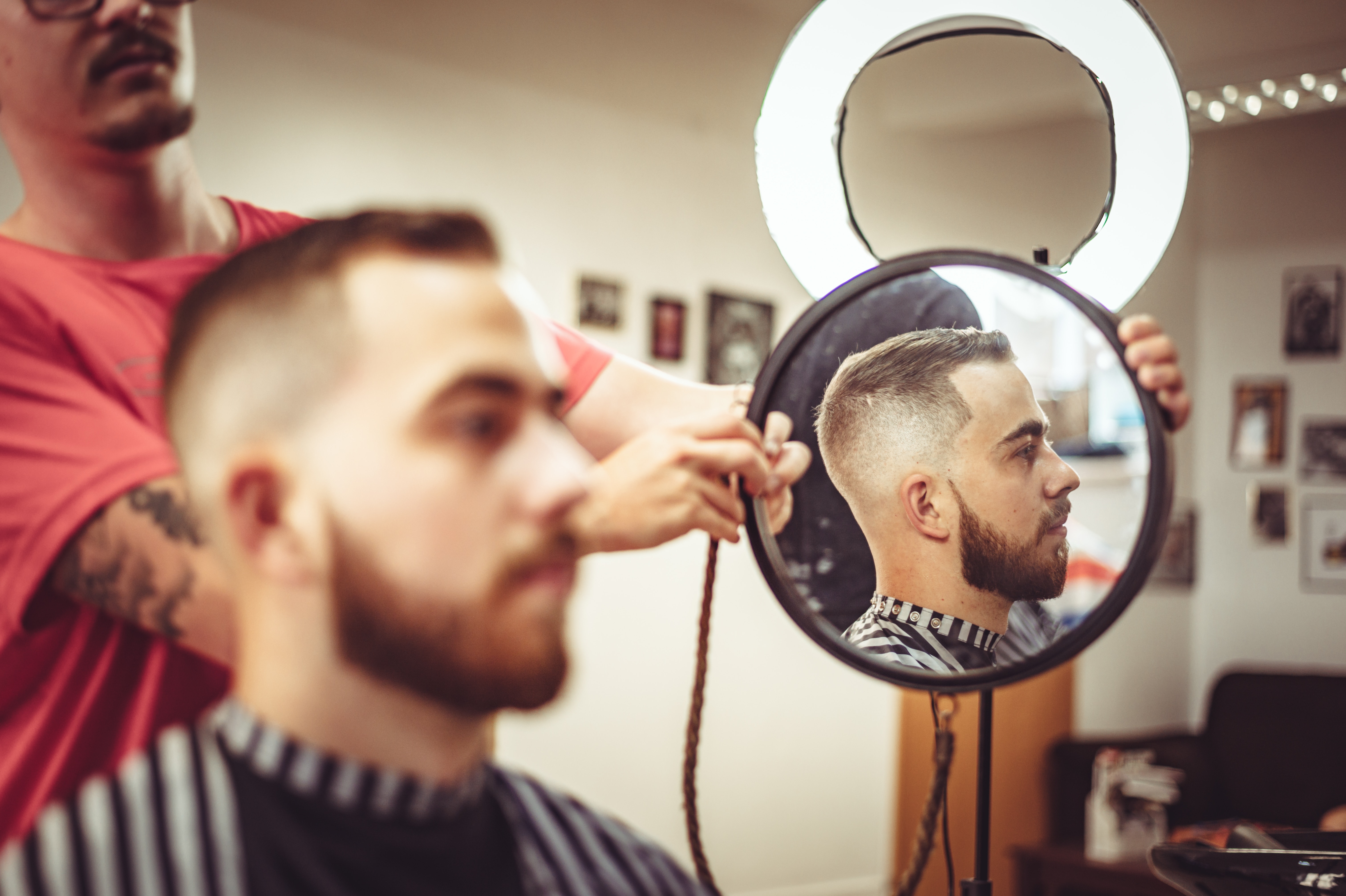 Barber holds up a mirror to his client.