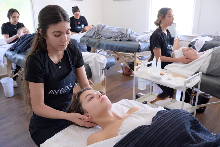 woman receives a facial massage from an esthetician at an Aveda Institute